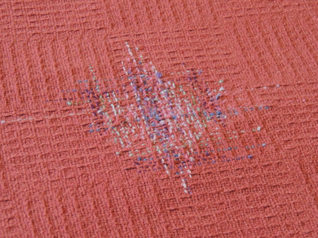 Close up view of a hand-darned area on a blanket