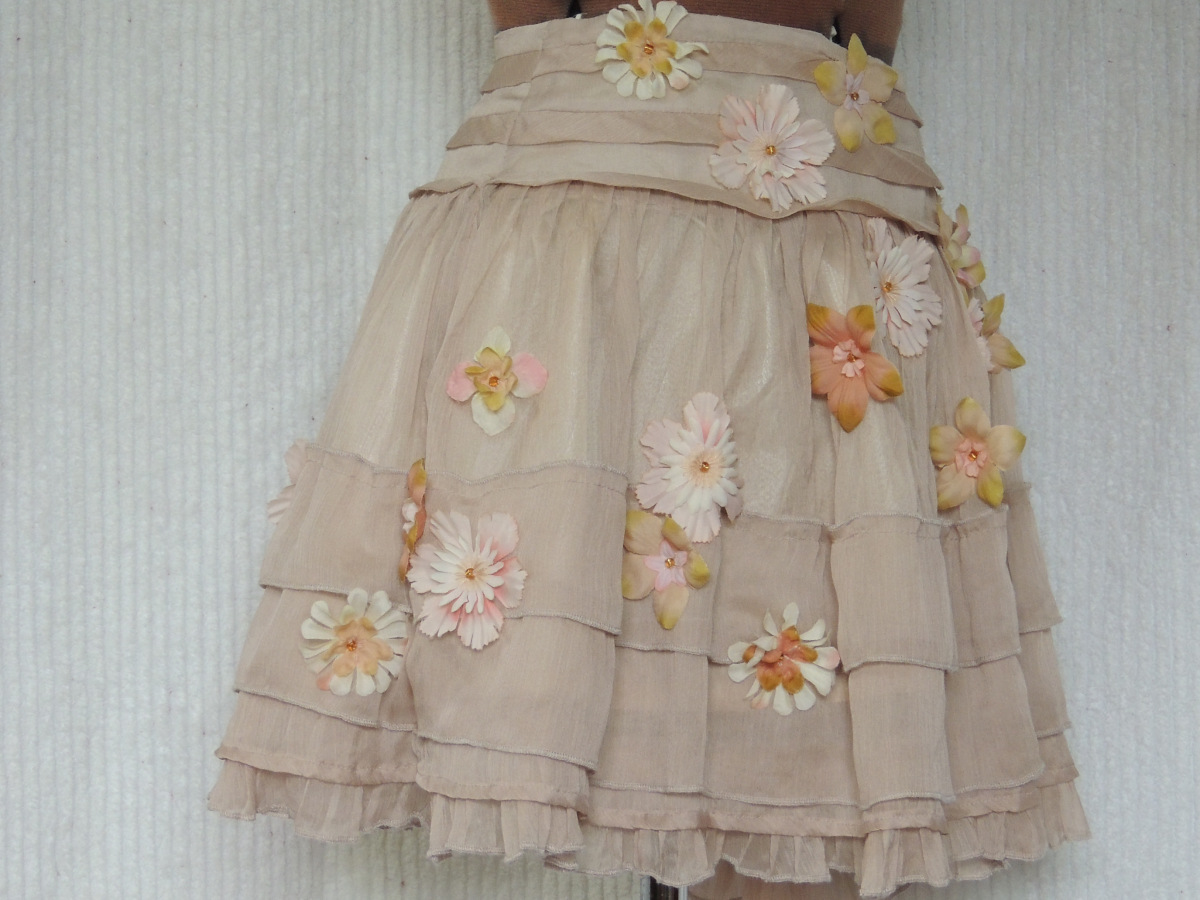 A pink skirt has cloth flowers sewn on it to cover up stains.