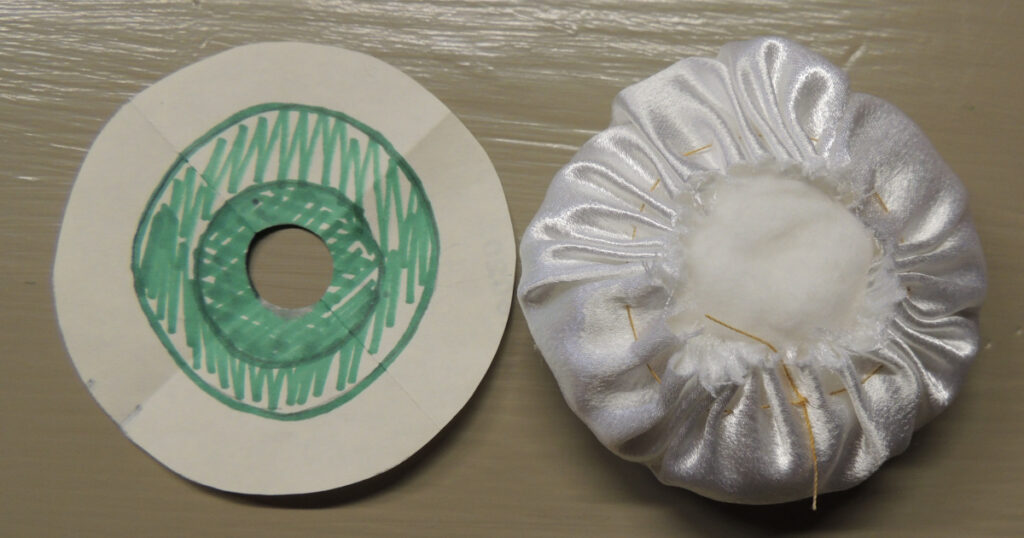 The back of a gathered and stuffed eyeball compared to the template.