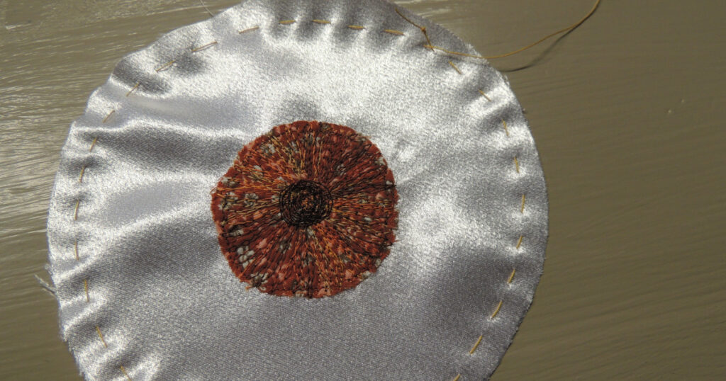 Gathering stitches shown around the edge of the eyeball piece before they are pulled tight.