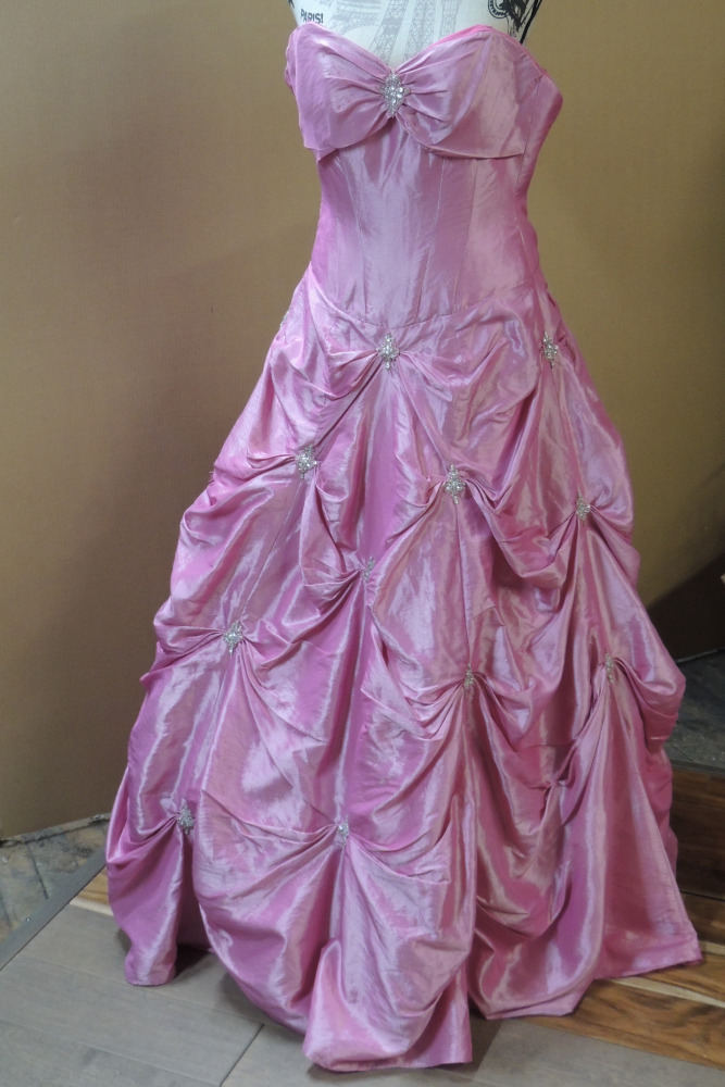 The original pink dress is displayed on a mannequin. It is made of bright pink taffeta with a very full skirt, accented with gathers and beaded medallions